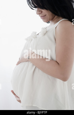 Pregnant Hispanic woman holding estomac Banque D'Images