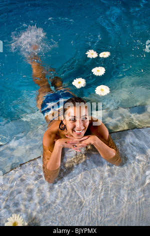 Portrait of mid-adult woman in pool avec des fleurs blanches Banque D'Images