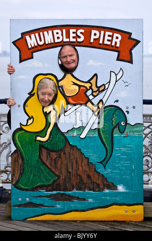 Couple de retraités à la photo si signe à Mumbles Pier Swansea Galles du Sud Banque D'Images