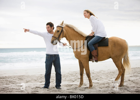 L'homme et la femme à cheval sur la plage Banque D'Images