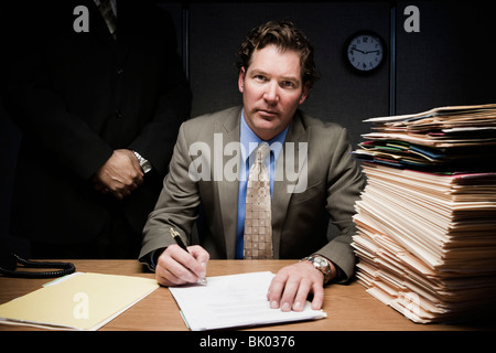 Man doing paperwork avec l'homme derrière lui Banque D'Images