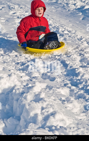 Les jeunes enfants des familles sur des traîneaux snowy city park hillside. Banque D'Images