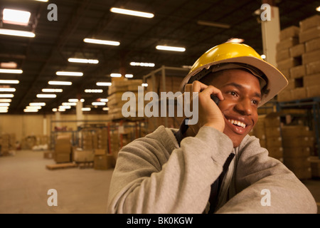 Black man talking on cell phone in warehouse Banque D'Images