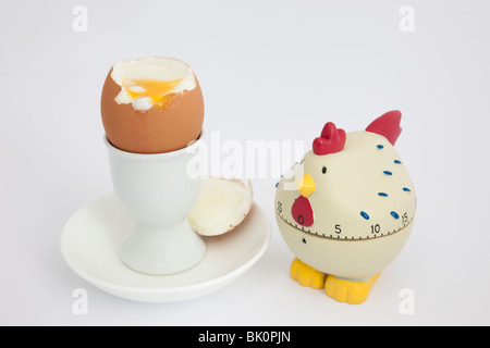 Minuteur oeuf de poule avec un oeuf mou ouvert dans une tasse sur fond blanc Banque D'Images