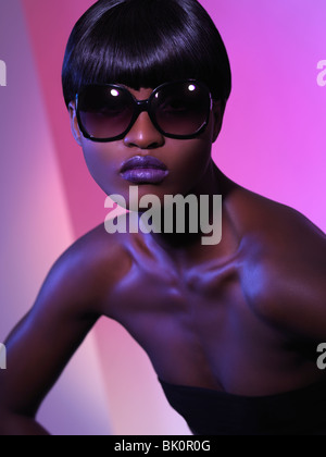 Belle jeune femme en noir sur fond violet lunettes Banque D'Images