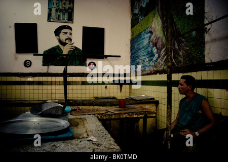 Un homme se tient devant un portrait de la leader révolutionnaire Che Guevara, accrochées sur le mur d'un marché à la Havane, Cuba. Banque D'Images