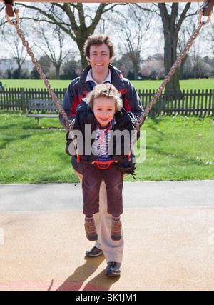 Père et fils jouant sur la balançoire dans un parc de Londres Banque D'Images