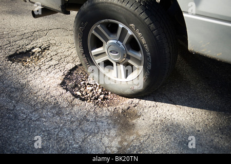 Une voiture entre dans un nid-de-poule dans une rue de Philadelphie, PA le mercredi, 31 mars, 2010. (© Frances M. Roberts) Banque D'Images