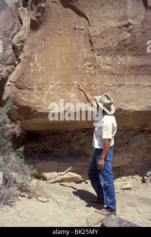 Le sei guide Indien pointant vers l'ancienne petrolyphs Anasazi, Ute Mountain Tribal Park, Colorado, États-Unis Banque D'Images