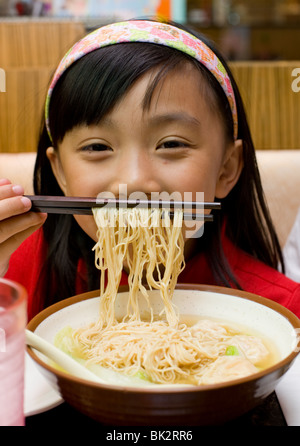 Jeune chinoise de manger des crevettes wonton et soupe de nouilles avec des baguettes à Chi Cafe à Chicago, IL Banque D'Images