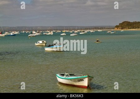 Bateaux ancrés dans le port de Sorrente, Mornington Peninsula, Victoria, Australie.Un homme lignes à son bateau dans un petit canot Banque D'Images