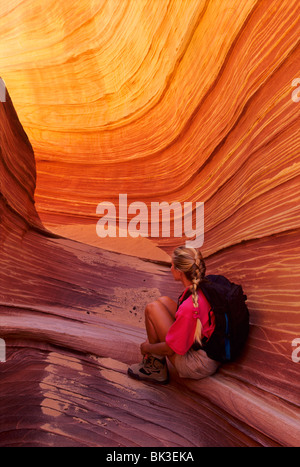 Une femme admire la chaude lumière reflétée dans un étroit canyon dans la région sauvage de Vermilion Cliffs dans le nord de l'Arizona. Banque D'Images