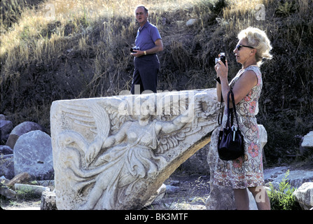 Touriste américain à côté d'en bas-relief de femme ailée tenant couronne et de plume. Éphèse, Turquie, octobre 1971 Banque D'Images