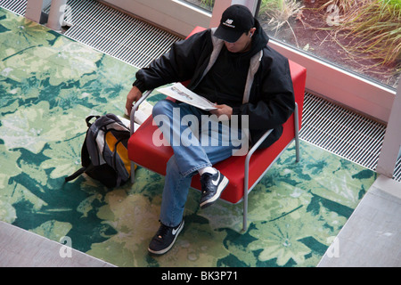 Man reading newspaper in salle de lecture publique de la branche principale, la Bibliothèque Publique de Seattle, Seattle, Washington Banque D'Images