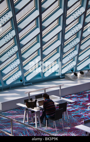 Femme au bureau avec lumière naturelle de plafond de verre et le mur de succursale principale de la Bibliothèque Publique de Seattle, Seattle, Washington Banque D'Images