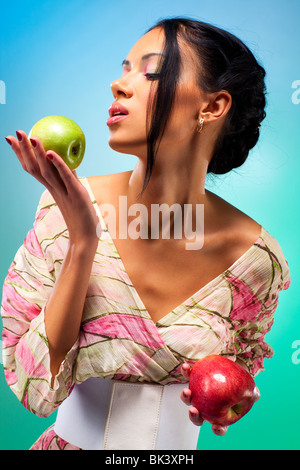 Jeune femme avec deux pommes. Riche des couleurs vives. Banque D'Images