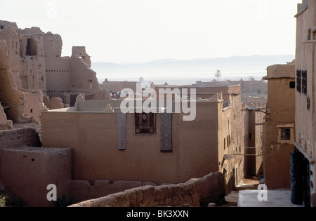 Scène de rue de village, avec des tapis qui pèsent sur un mur, Province de Ouarzazate, Maroc Banque D'Images