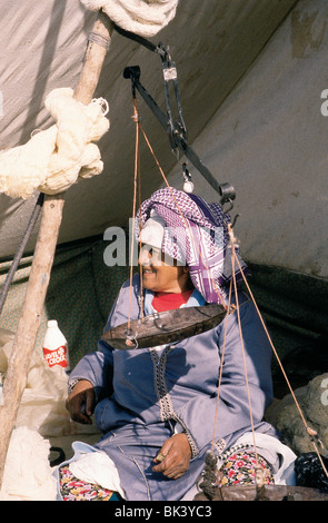 Une personne avec une balance portant des vêtements et une coiffe de tradition sur un marché près de Safi, au Maroc Banque D'Images