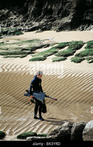 L'homme sur une plage portugaise de porter une combinaison isothermique et la tenue de plongée en apnée, Portugal Banque D'Images