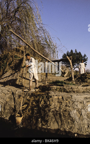 Les hommes à l'aide d'un shadoof égyptien (un outil d'irrigation historique) au Dr Ragab's Village pharaonique (A Living History Museum) au Caire Banque D'Images