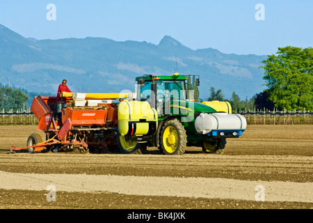 La plantation de pommes de terre avec un semoir 4 rangs d'être tiré par un tracteur John Deere au printemps dans Skagit County, Washington Banque D'Images