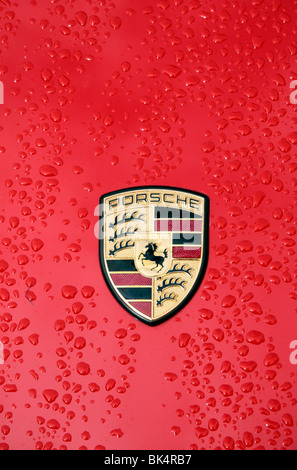 Close up des gouttes et l'insigne ou le logo d'une Porsche rouge. Banque D'Images