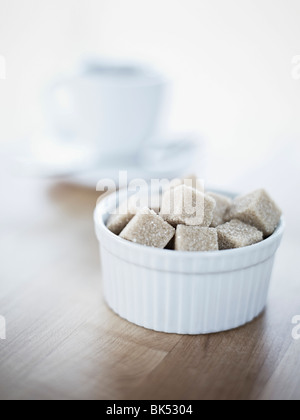 Bol de sucre brut en cubes, tasse de café à l'arrière-plan Banque D'Images