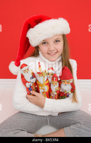 Portrait of Girl Holding Santa Ornaments Wearing Santa Hat Banque D'Images