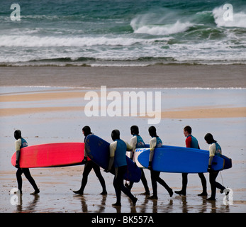 Surfers carrying leurs planches par un jour de vent sur la plage de Fistral à Newquay en Cornouailles. Photo par Gordon 1928 Banque D'Images