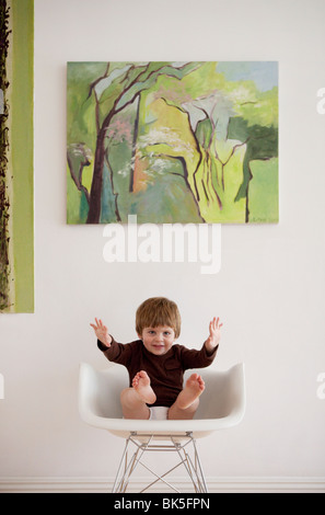 Bébé en chemise brune sur rocking chair moderne Banque D'Images