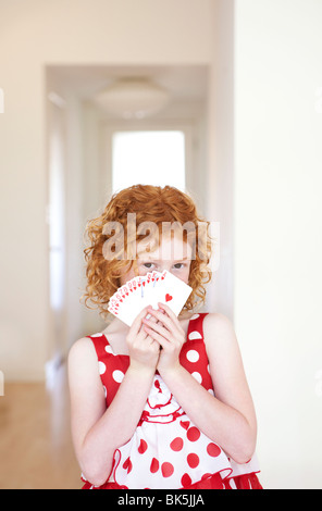 Fille en rouge et blanc polka dotted dress peeking sur jeu de cartes Banque D'Images