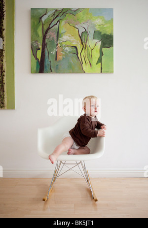 Bébé en chemise brune sur rocking chair moderne Banque D'Images