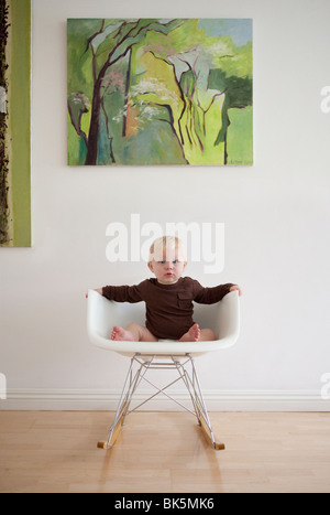 Bébé en chemise brune sur rocking chair moderne Banque D'Images