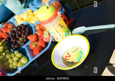 Repas pique-nique en plein air ou sur un tableau noir avec des bols, tasses en plastique bleu, et des bidons avec des fruits et de la salade Banque D'Images