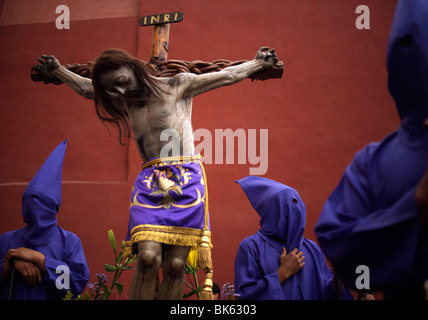 Une statue de Jésus Christ crucifié est entouré de pénitents lors d'une procession de la semaine sainte à Oaxaca, Mexique Banque D'Images