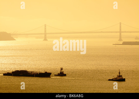 Cargo avec les remorqueurs sur l'océan Pacifique avec le Pont de la baie en arrière-plan-San Francisco, Californie, USA. Banque D'Images