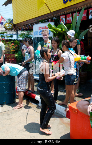 Farang recouvert de poudre jette un seau d'eau sur un thai dame à Songkran Festival Thaïlande Koh Phangan Banque D'Images