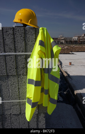 Casque et gilet hivis sur une pile de blocs de construction en béton breeze sur chantier de construction en Irlande du Nord, Royaume-Uni Banque D'Images