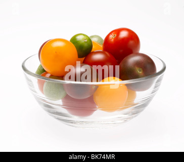 Heirloom tomates cerise dans un bol en verre clair sur fond blanc Banque D'Images