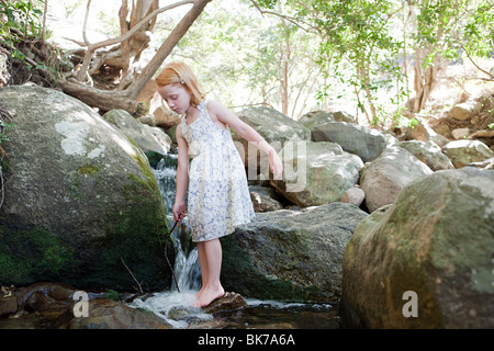 Girl standing on rock in river Banque D'Images