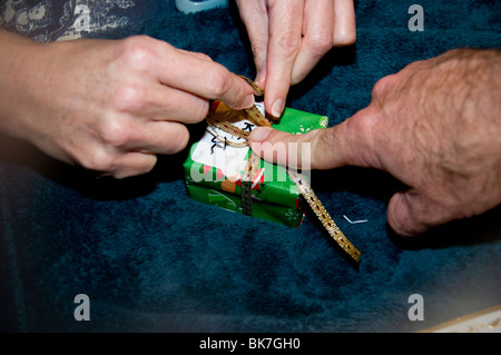 Libre de woman's hands et la main d'un homme comme ils envelopper un cadeau de Noël. Banque D'Images