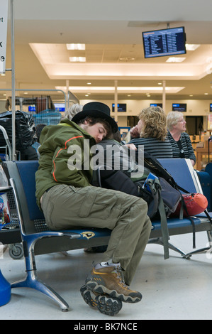 L'homme de dormir sur un aéroport siège alors qu'est le vol est annulé Banque D'Images