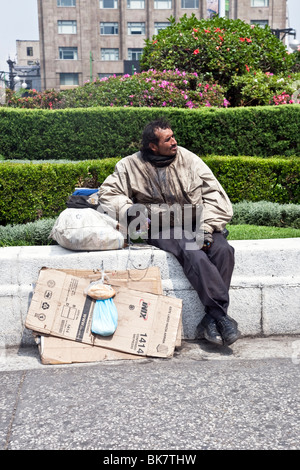 Sale mais se contenta sans-abri assis avec effets personnels in sunlit jardin en face de l'Palacio de Bellas Artes Mexico City Banque D'Images