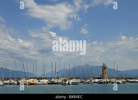 Marina avec des yachts et phare à Desenzano del Garda sur le lac de Garde Italie Monte Baldo avec de la neige sur le sommet à distance Banque D'Images