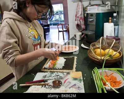 Jeune femme d'adolescent la préparation des sushis dans la cuisine Banque D'Images