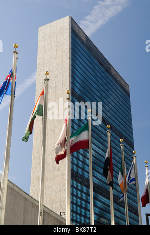 NEW YORK, NY, États-Unis — un ensemble de drapeaux colorés représentant les états membres des Nations Unies flottent devant l'emblématique bâtiment du Secrétariat de l'ONU, la structure principale du complexe du Siège de l'ONU à New York. Cette impressionnante manifestation d'unité internationale s'inscrit dans le contexte de l'architecture moderne et épurée qui est devenue un symbole de la diplomatie et de la coopération mondiales. Banque D'Images