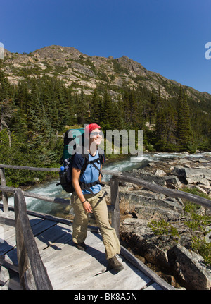 Jeune femme la randonnée, traverser un pont de bois, randonneur avec sac à dos, col Chilkoot, historique, près de de la Piste-Chilkoot Banque D'Images