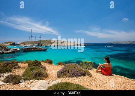 Femme à la recherche sur des bateaux d'excursion dans le lagon bleu de Comino, Malte, Europe Banque D'Images