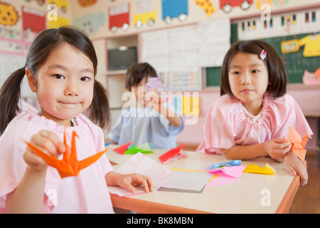 Les enfants de maternelle Holding Paper Crane Banque D'Images