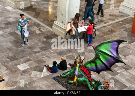 Deux petits garçons mexicains posent pour leur fière maman en face de dragon fantastique sculpture dans la pièce au Palais des Gouverneurs Oaxaca Banque D'Images